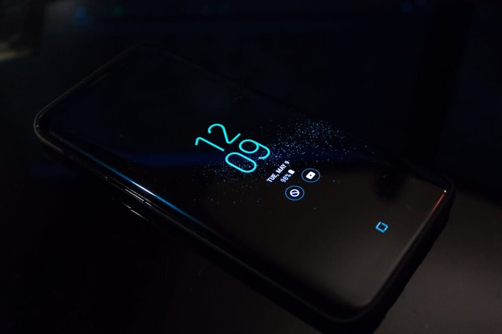 Close-up of a smartphone in the dark displaying digital clock and notifications.